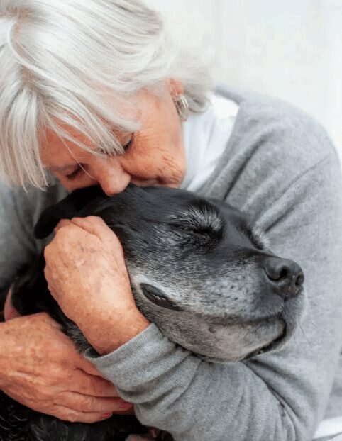 A woman nuzzling a senior rescue dog